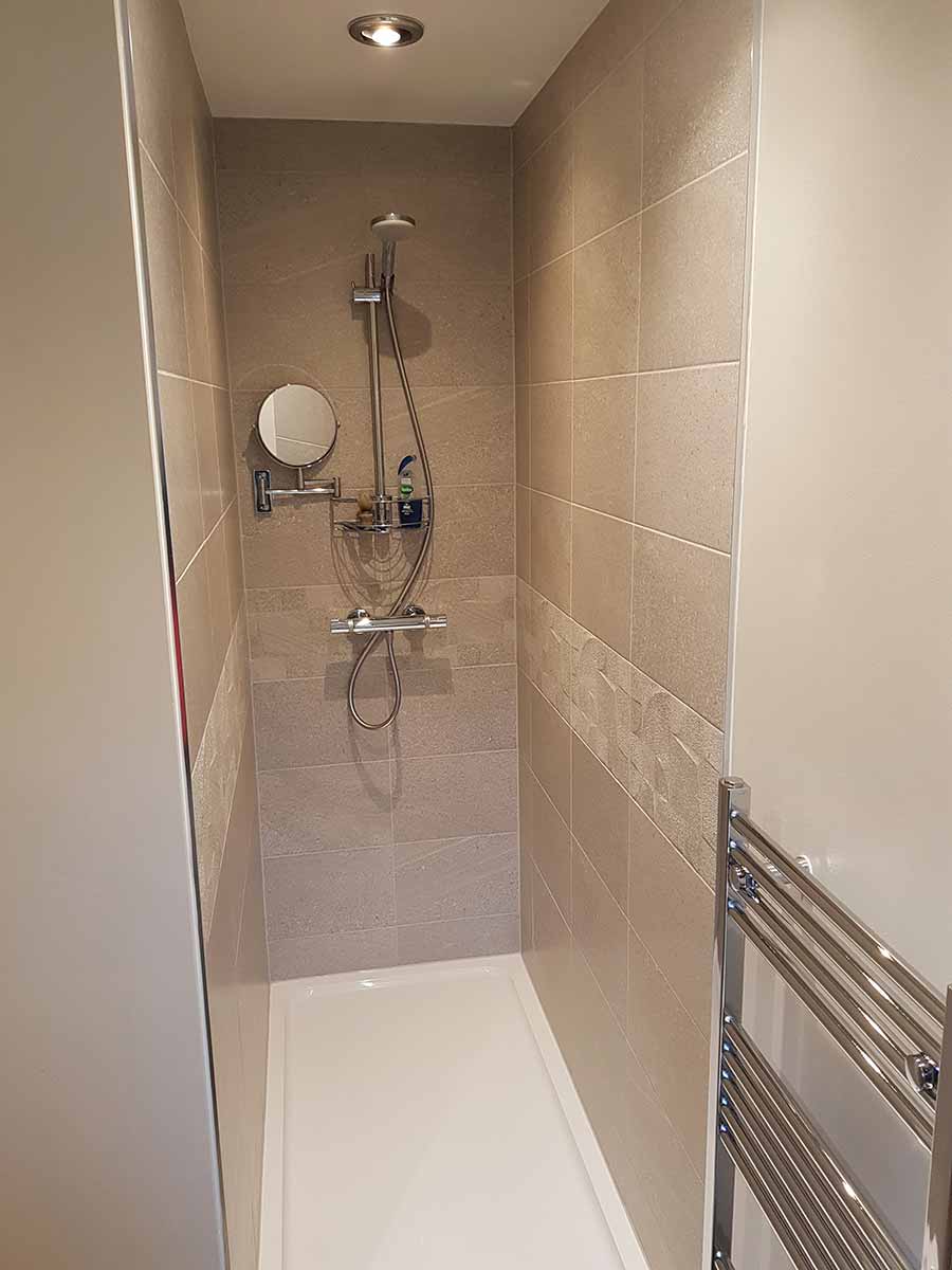 Tiled shower with a thermostatic bar