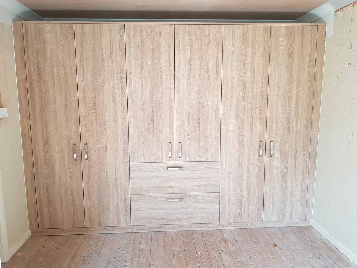 Wall of fitted oak-effect wardrobes